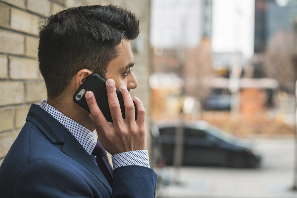 A man in a suit taking a call on his mobile phone in a city street
